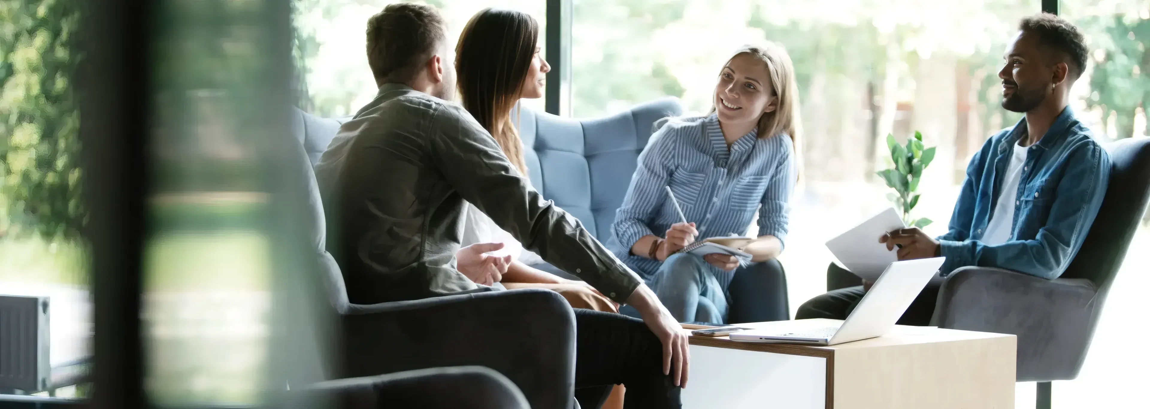 Four colleagues talking together in a bright, modern office lounge